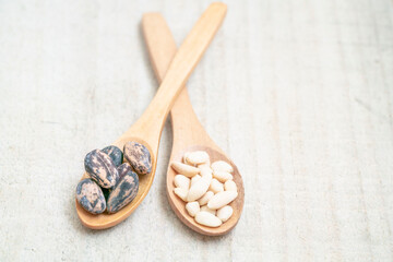 Fototapeta na wymiar shelled and whole pine nuts in spoon on the wooden background with copy space