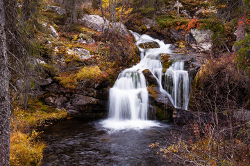 Beautiful Kullaoja waterfall flowing in the middle of autumn colors. Shot near Salla, Northern Finland. 
