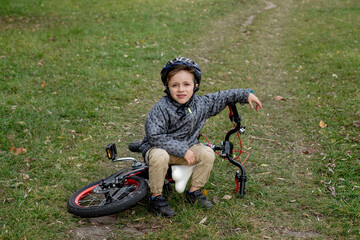 Obraz premium Portrait of smiling boy in a helmet with a bicycle in the park