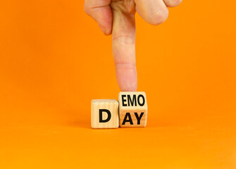 Demo day symbol. Businessman turns a wooden cube with concept words 'demo day' on a beautiful orange table, orange background. Copy space. Business and demo day concept.