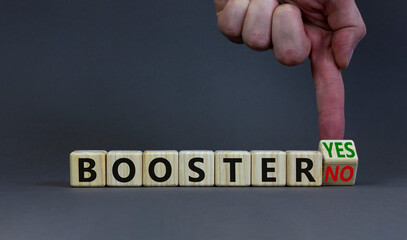Covid-19 booster vaccine shot yes or no symbol. Doctor turns a wooden cube and changes words booster no to booster yes. Beautiful grey background, copy space. Covid-19 booster vaccine shot concept.