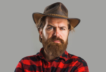 Handsome man in cowboy hat. Western style portrait. Bearded macho in plaid shirt. American cowboy.