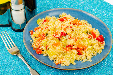 Vegetarian couscous pilaf with vegetables on blue plate. Studio Photo