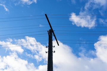 Old wooden pole of power transmission against a background of blue sky with clouds. There are several reasons. Background. Texture.