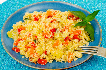 Vegetarian couscous pilaf with vegetables on blue plate. Studio Photo