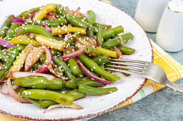 Vegetarian green bean pod dish with red pickled onions and sesame seeds. Studio Photo
