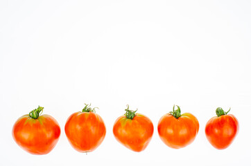 Red tomatoes in shape of heart on white background. Studio Photo