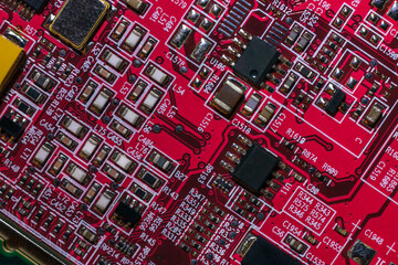 Macro close-up shot of a microchip, processor (CPU) on a red high-tech electronic printed circuit board (PCB), computer motherboard with components inside an electronic device, part of a video card