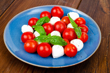 Delicious Italian caprese salad with basil, mozzarella and cherry tomatoes. Studio Photo.