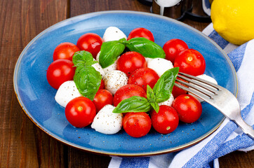 Delicious Italian caprese salad with basil, mozzarella and cherry tomatoes. Studio Photo.
