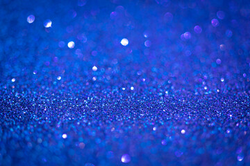 Blue shiny glitter texture. Selective focus. Glowing surface, sparkle lights and bokeh effects. Christmas and festive background