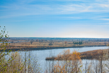 Autumn view of the blue river and yellow vegetation. Autumn landscape in bright sunny.
