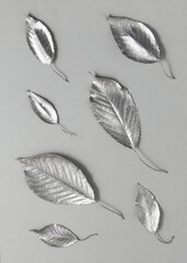 Silver leaves on gray background. Minimalistic modern composition. Nature flat lay idea.