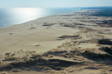 A view from a height of a narrow and long sandy saber-shaped strip of land separating the Curonian Lagoon from the Baltic Sea. Gray sand dunes of the Curonian Spit.