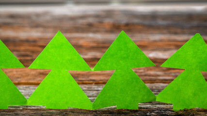 Green paper trees on wooden background