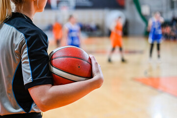 Woman referee keeps the ball during basketball match.