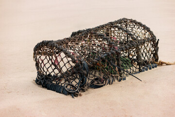 A discarded lobster trap or pot washed ashore onto a beach