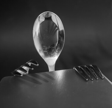A spoon and two forks at the table are being prepared for a meal. Creative still life concept. Black and white design.