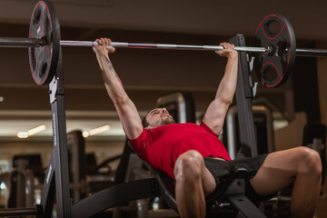 Fit young man lifting barbells working out in a gym
