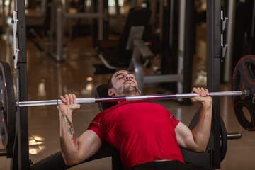 Fit young man lifting barbells working out in a gym