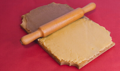 Dough for making homemade gingerbread cookies on a wooden board on a red background.