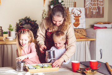 Fototapeta premium Mom and children are preparing cupcakes in the kitchen.