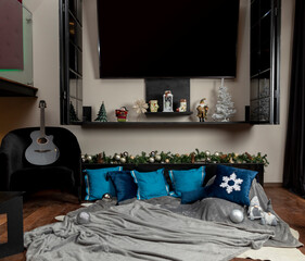 Christmas-themed cushions on a blanket on the floor of a living room, with a guitar by the side