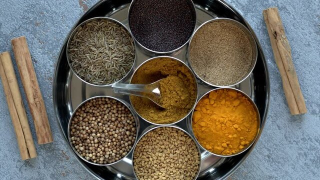 Masala Dabba Indian typical spice box. Spices assortment in round tin. Top view, table spin.