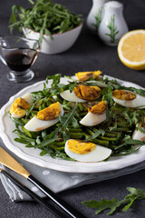Salad with avocado, arugula and eggs on a white plate on a dark gray background