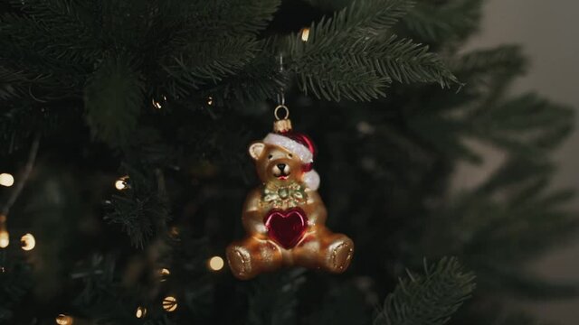 Close-up of woman's hands decorating Christmas tree wist bear toy