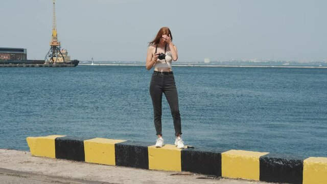 beautiful young woman photographer with red hair walks in the port of Odessa