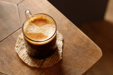 espresso coffee in a glass mug with cheesecake on a wooden background

