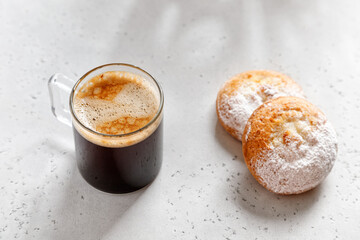 one espresso coffee in a glass mug with cake on a light grey  background