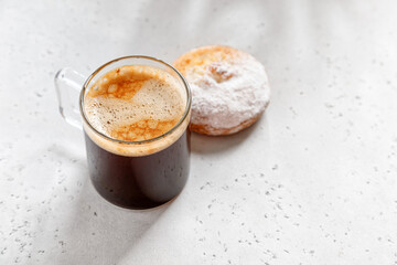 one espresso coffee in a glass mug with cake on a light grey  background