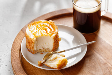 espresso coffee in a glass mug with cheesecake on a wooden tray on a gray background