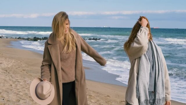 beautiful girls walk near the sea. Woman couple having a good time next to the ocean in cold sunny day 
