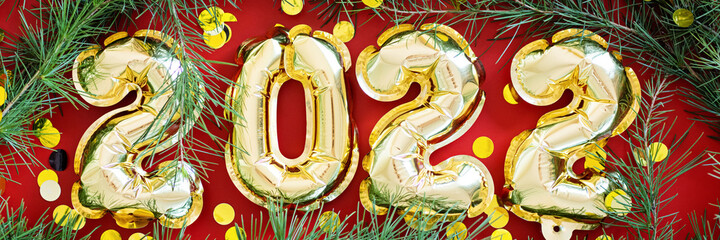 Happy new year 2022 background. Metallic balloons golden color on red paper. Flat lay, top view, mockup, overhead. Winter holiday celebration