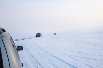 Group of cars drives on an icy winter road across the lake. Winter road. Extreme ride.