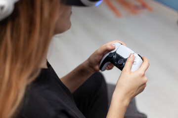 young woman in virtual reality helmet with gamepad joystick playing