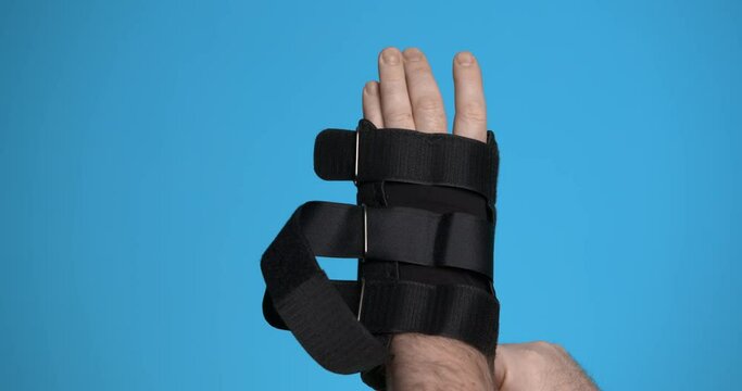 A man puts on a wrist orthosis and fastens the belts. Close-up.