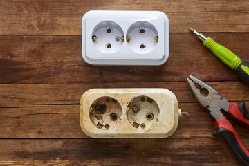 Burnt out electrical outlet and new to replace on a wooden background