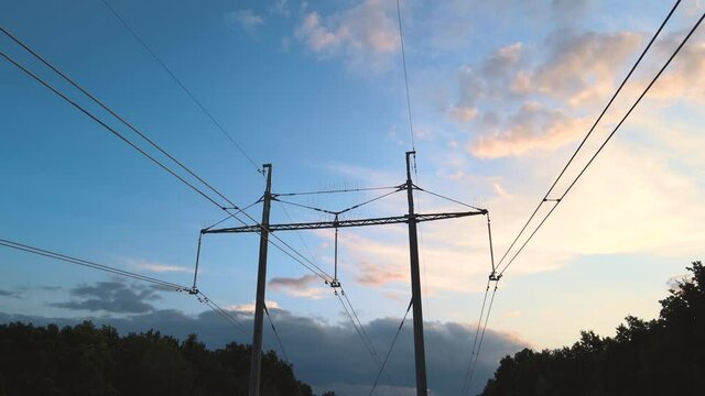 Dark silhouette of high voltage tower with electric power lines at sunset. Transfer of electricity concept.