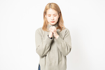 手を組んでお願いするセーターを着た女性