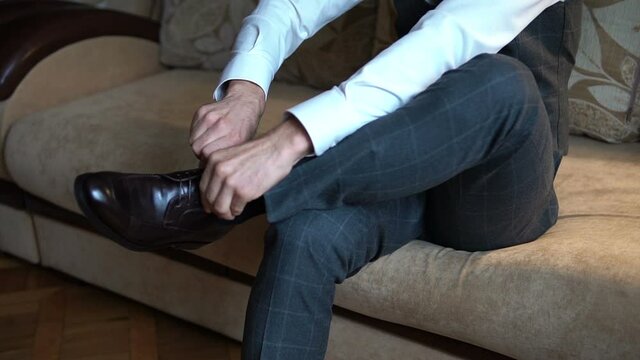 A man in a business suit puts on shoes.