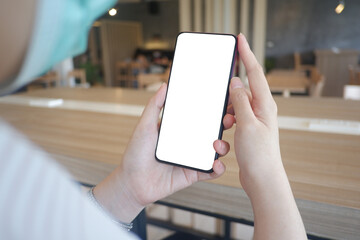 Mockup picture of business woman’s hands holding smart phone with white blank screen in modern place