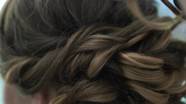 Hair curling. The woman uses a curling iron. Hairdresser makes female hair styling. Beautiful hairstyle for the Bride, before the date.