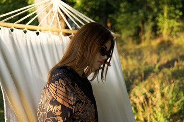 woman in sunglasses lies in a hammock outdoors summer lifestyle