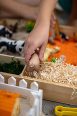 Touch drawer with rainbow rice inside. Children hand touch the texture. Montessori material concept for toddlers.