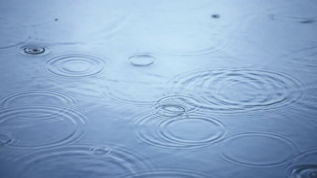 Rippled rain drops on water surface in super slow motion