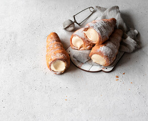 Puff pastry horns filled with custard on a light background with space for text. Top view